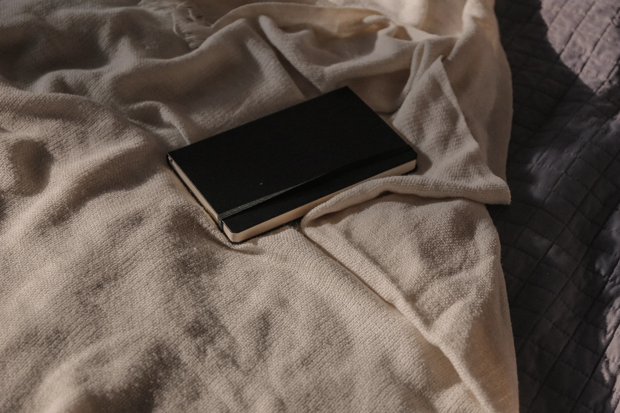 A notebook resting on a soft linen throw in morning light
