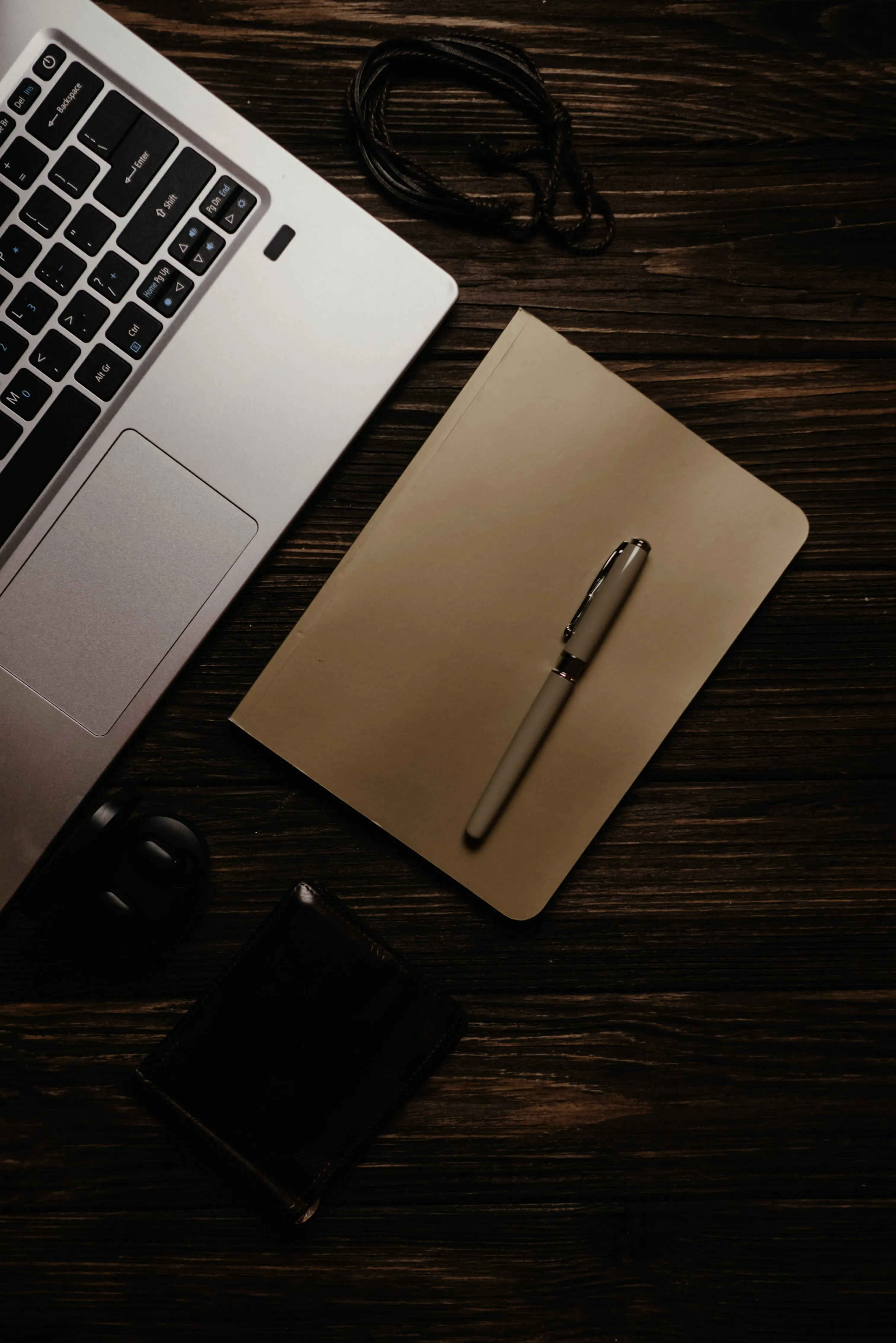 A notebook and beige pen on a wooden workspace